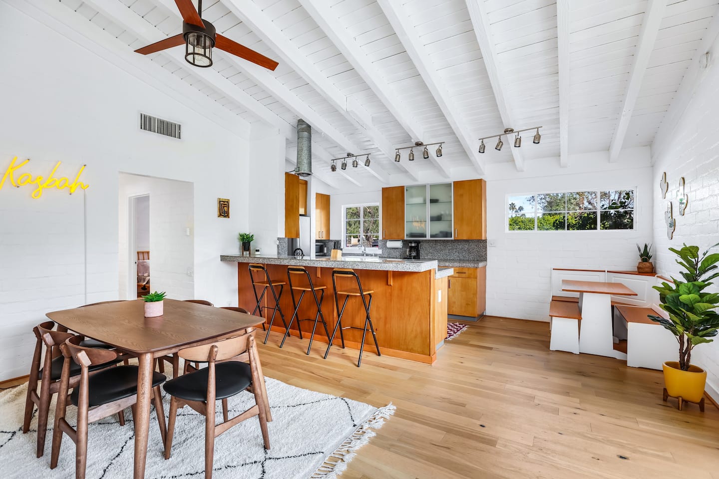 Open kitchen and dining room with timber cabinets and a vaulted white ceiling